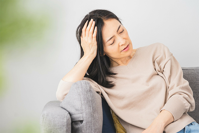 ソファにもたれかかり、不調そうな様子の女性