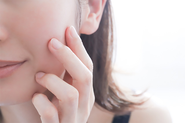 肌をさわっている、笑顔の女性