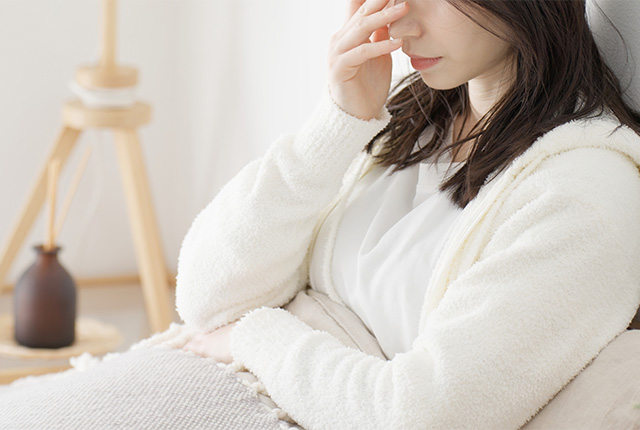 ソファで休みながら顔に手を当てている女性の様子